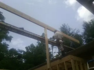 Carpenter setting a ridge beam over a new addition frame in Gurley