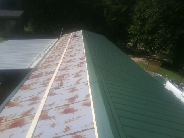 Old rusted panels beside newly installed green metal roofing — Wind Damage Roof Repair by Roofing Brothers in Gurley