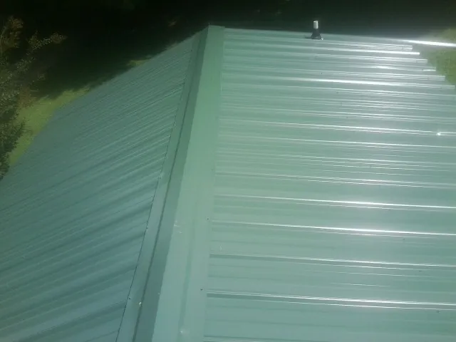 New green metal panels meeting at the ridge of a roof — Flat Roof Repair work by our crew in Gurley