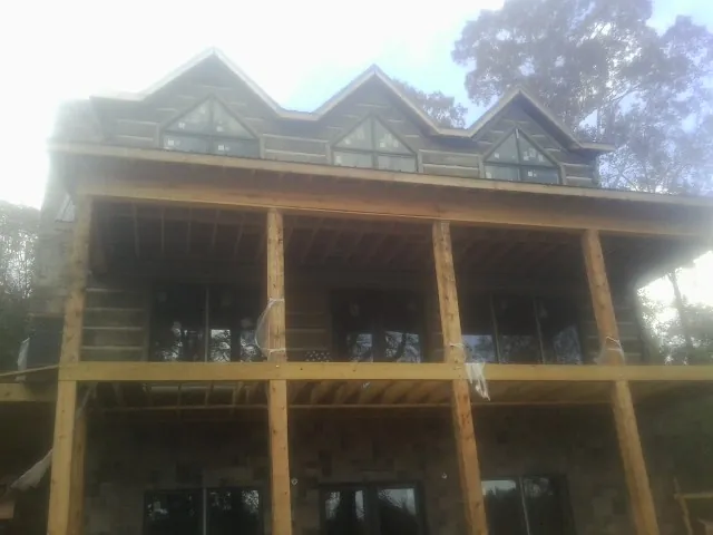Dormers and porch framing on a large log home under construction — Roof Coating work by our crew in Gurley