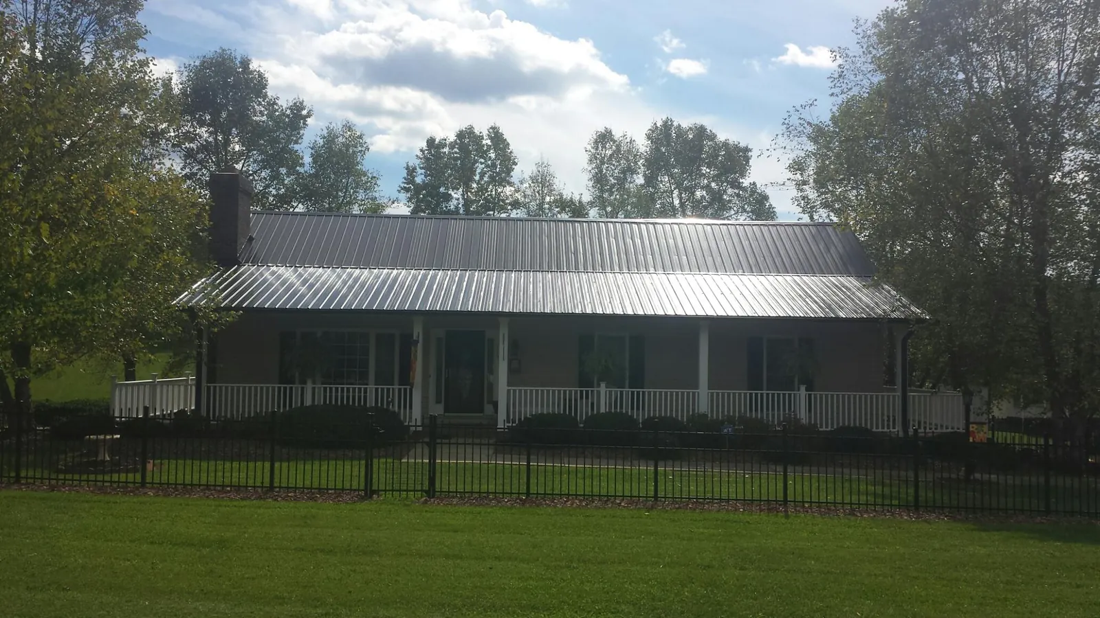 Gray metal roof on a brick ranch with a full width front porch — Gutter Guard Installation work by our crew in Gurley