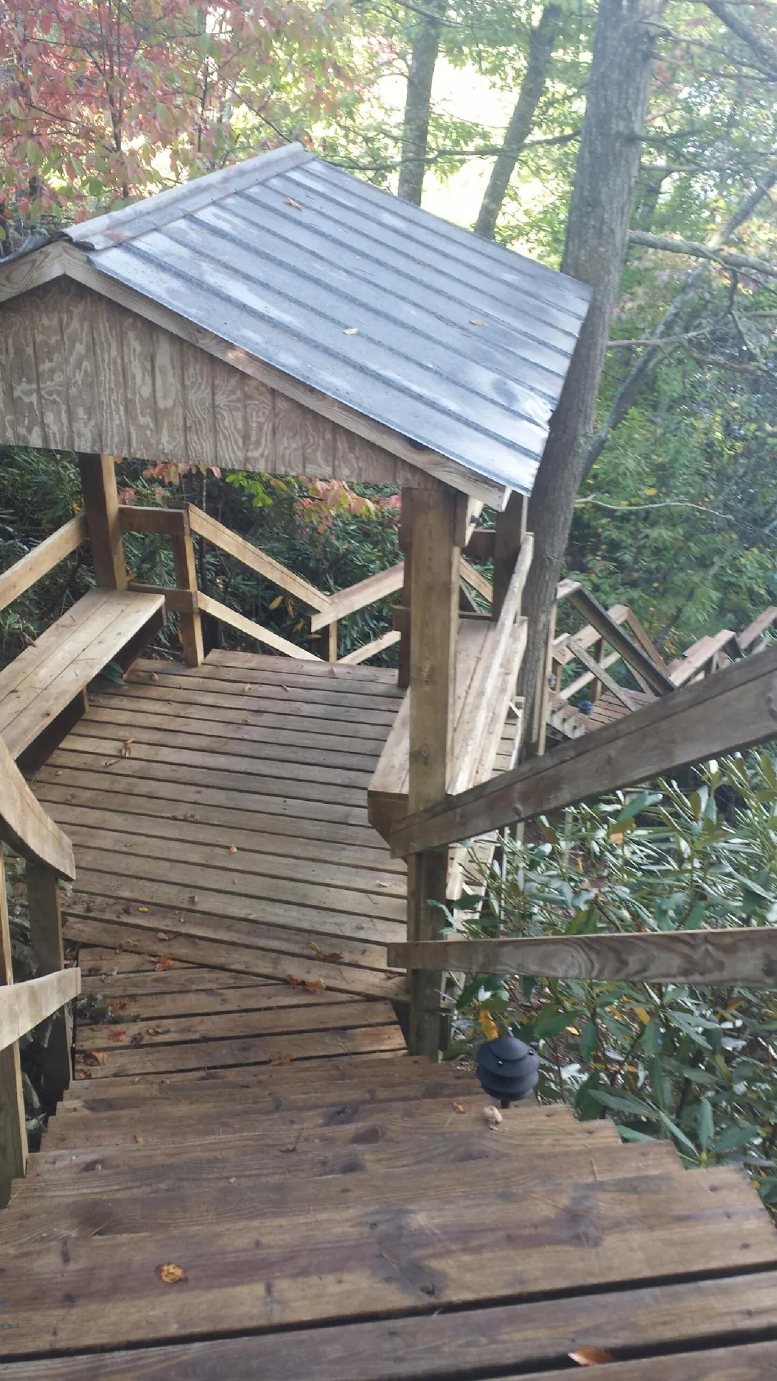 Metal roofed shelter over wooden steps on a wooded walkway — Skylight Repair & Installation work by our crew in Gurley