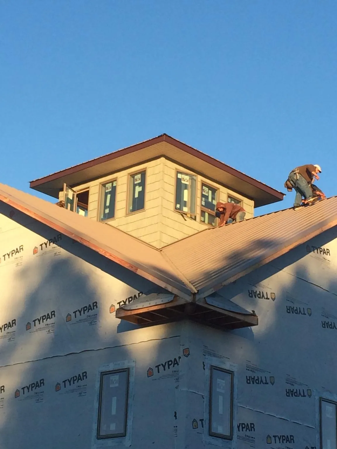 Roofers working around a rooftop cupola on a new metal roof at sunset — Roof Waterproofing in Gurley by Roofing Brothers